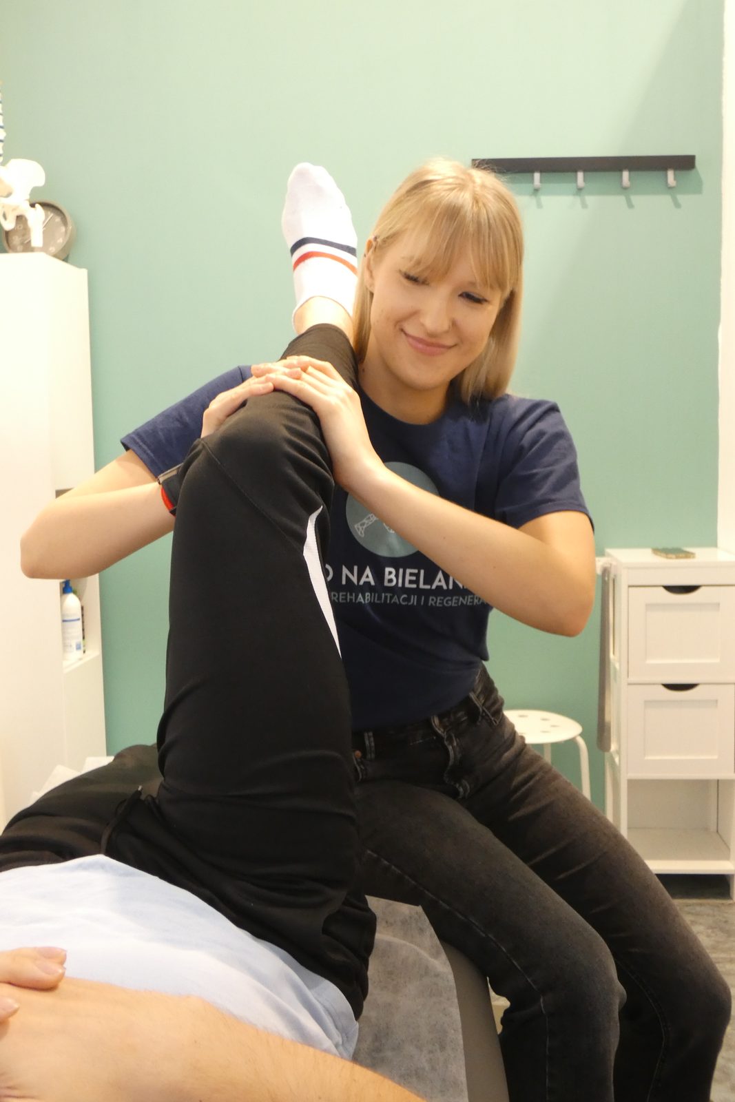 Aleksandra Szelaszuk prowadzi mobilizację biodra i nogi pacjenta