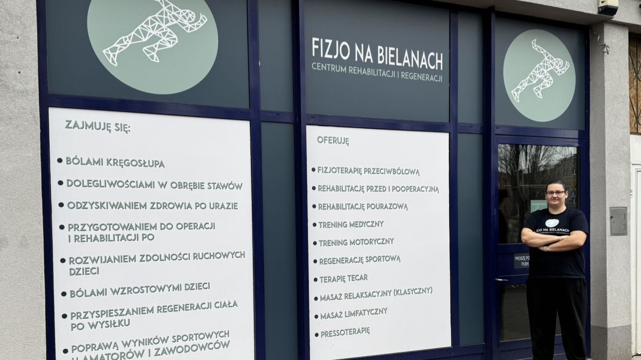 Wejście do Fizjo na Bielanach od ul. Marymonckiej; na szybach listy „Zajmuję się” i „Oferuję”, przed wejściem Małgorzata Kimso